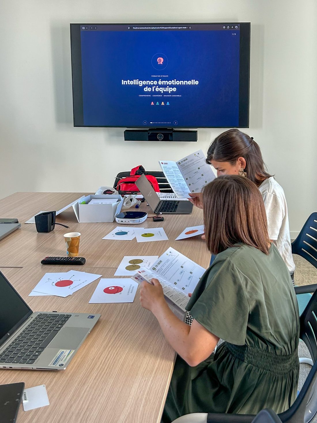 Deux participantes lisent leur livret pendant une formation « Intelligence émotionnelle de l'équipe », des cartes sur la table