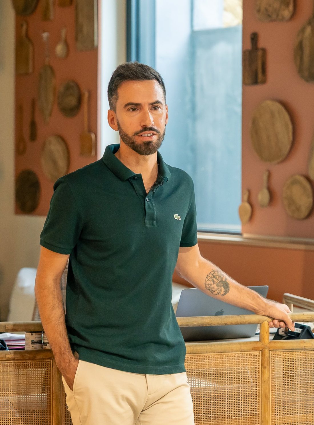 Sébastien Caradonna debout dans une salle de formation, une main appuyée sur un meuble en rotin