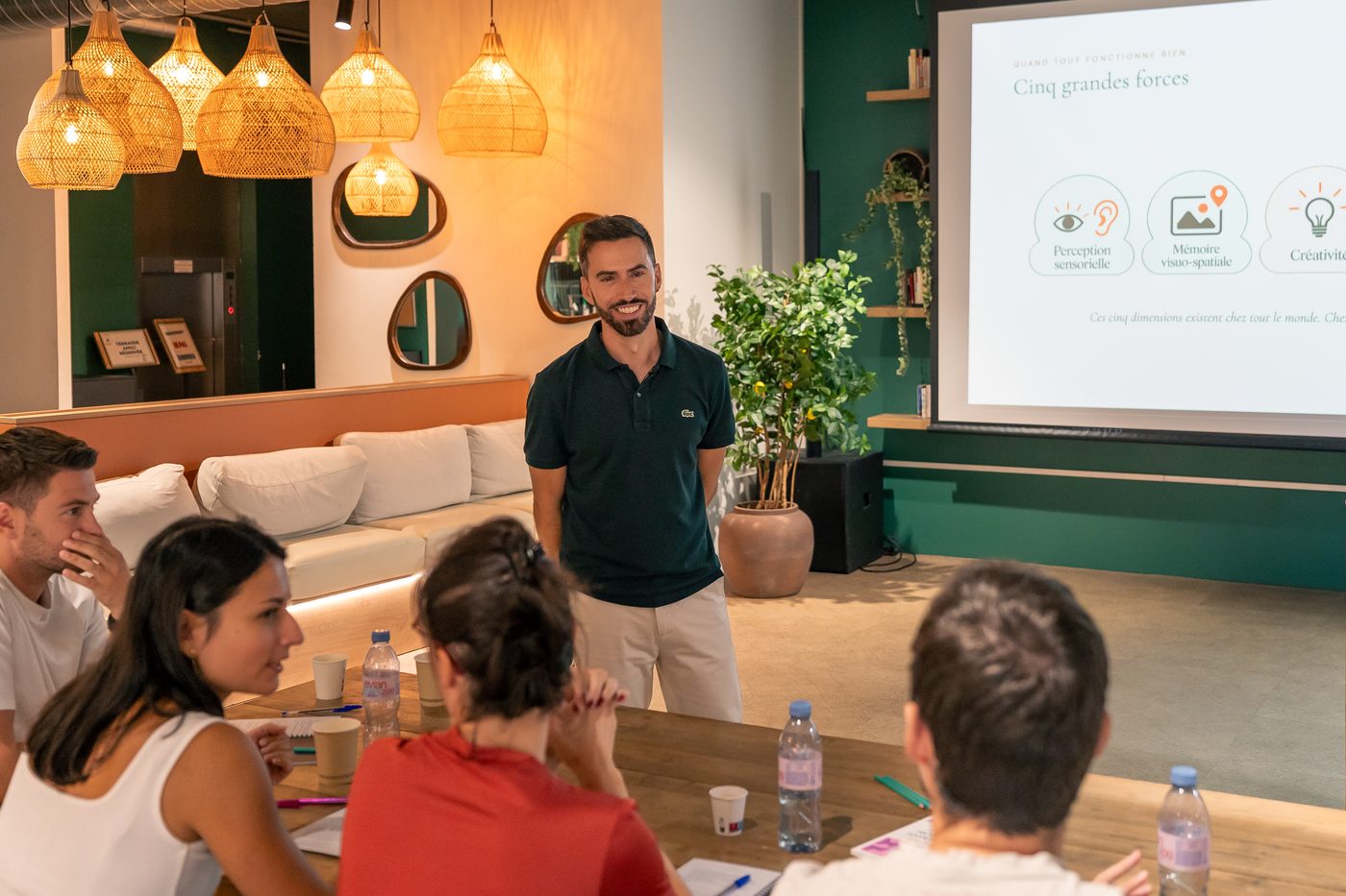 Sébastien Caradonna présente un support projeté à un groupe attablé